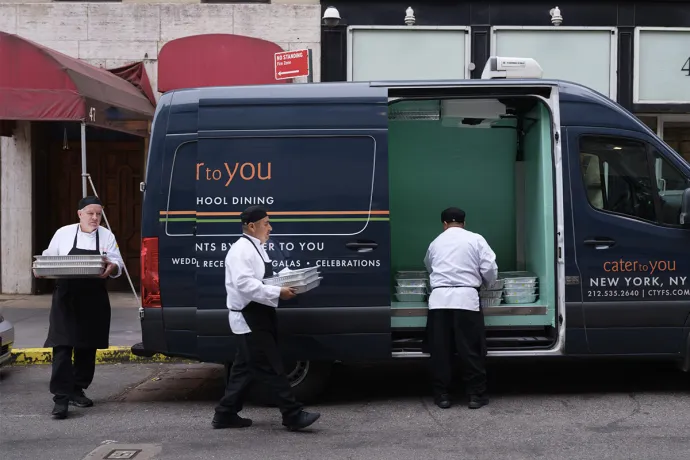 three chefs load a van with food in New York City