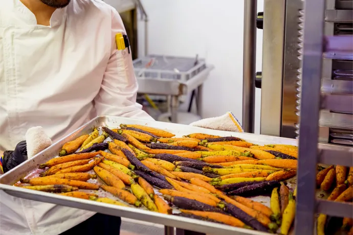 chef roasting carrots in a school kitchen